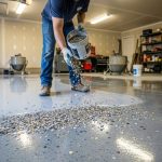 Worker applying decorative color flakes onto wet epoxy coating on garage concrete floor