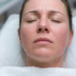 Woman gently soothing irritated skin after a chemical peel spa treatment