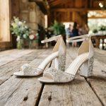 Crystal block bridal heels on rustic wood at a Texas wedding venue.