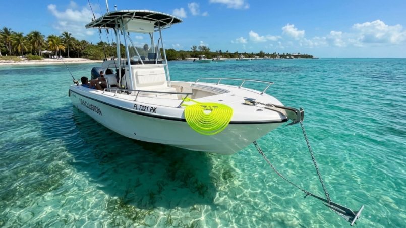 Boat anchored in turquoise Florida water with coiled anchor rope on deck.
