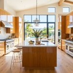 Bright modern California kitchen with polished oak wood cabinets reflecting natural sunlight.